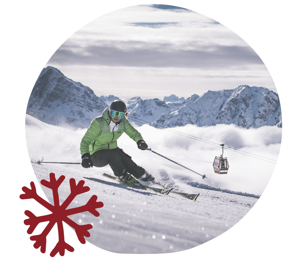 Almgasthof Geisler sulla Plose | Divertimento sugli sci, scuola di sci, parco per snowboarder e freestyler. L'immagine mostra uno sciatore con una giacca verde che effettua una curva a gomito su una pista della Plose e si gode l'abbondanza di neve. La neve brilla al sole, proprio come le montagne circostanti.