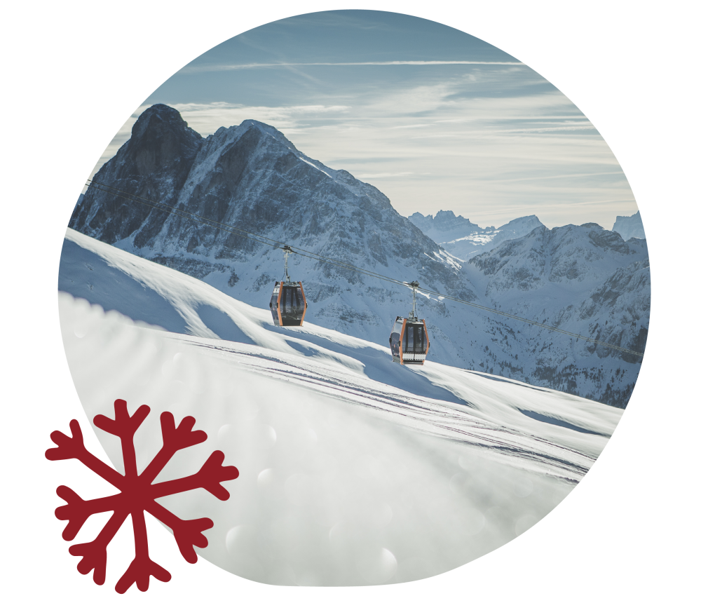 Das Bild zeigt eine Gondel der Kabinenbahn Plose, wie sie gerade Skifahrer auf die schneesichere Piste transportiert. Im Hintergrund verschneite und imposante Berge sowie einen strahlenden Himmel.