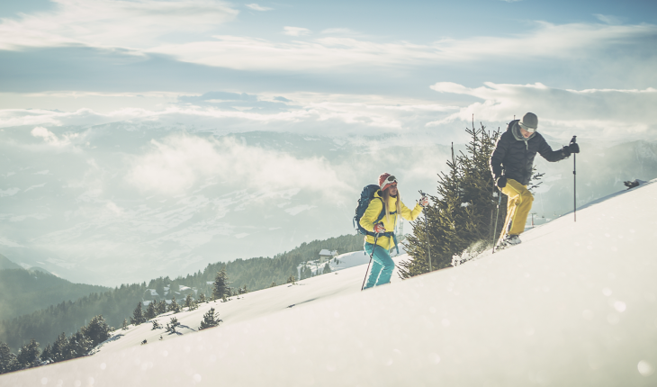 L'Almgasthof Geisler | è il luogo ideale per escursioni sciistiche sulla Plose e vacanze nella natura in inverno L'immagine mostra due persone che salgono con gli sci da alpinismo in un paesaggio profondamente innevato. Si sono lasciati alle spalle il limite degli alberi e godono di una vista favolosa sulle montagne dolomitiche circostanti della Valle Isarco.