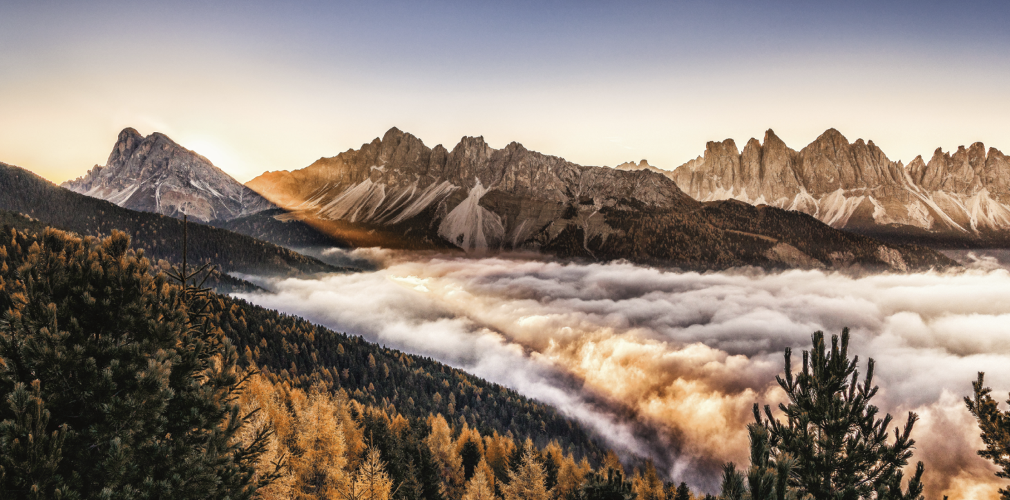 Almgasthof Geisler | La vacanza in montagna offre una vista panoramica libera sulle Dolomiti come Aferer e le Odle di Funes. L'immagine mostra la meravigliosa vista panoramica dall'Almgasthof Geisler sulle Dolomiti di Funes e Aferer Odle. Sotto di esse c'è la nebbia. I larici si stanno gradualmente tingendo di giallo, annunciando l'arrivo dell'autunno.